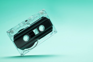 Photo of One audio cassette in air on turquoise background, closeup. Space for text