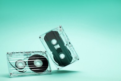 Photo of Audio cassettes in air on turquoise background, closeup. Space for text