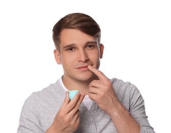 Photo of Young man applying lip balm onto his lips on white background