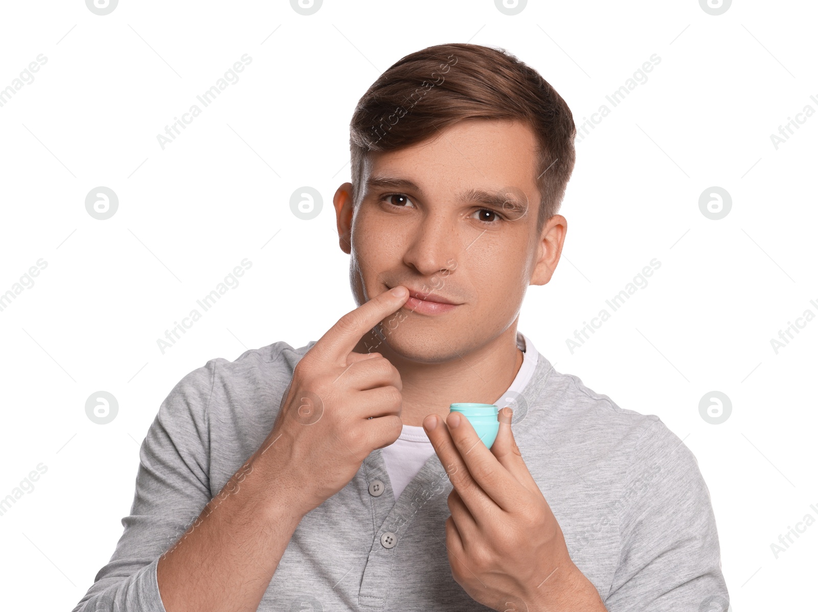 Young man applying lip balm onto his lips on white background Photo of Young man applying lip balm onto his lips on white background
