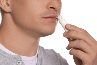 Photo of Young man applying lip balm onto his lips on white background, closeup