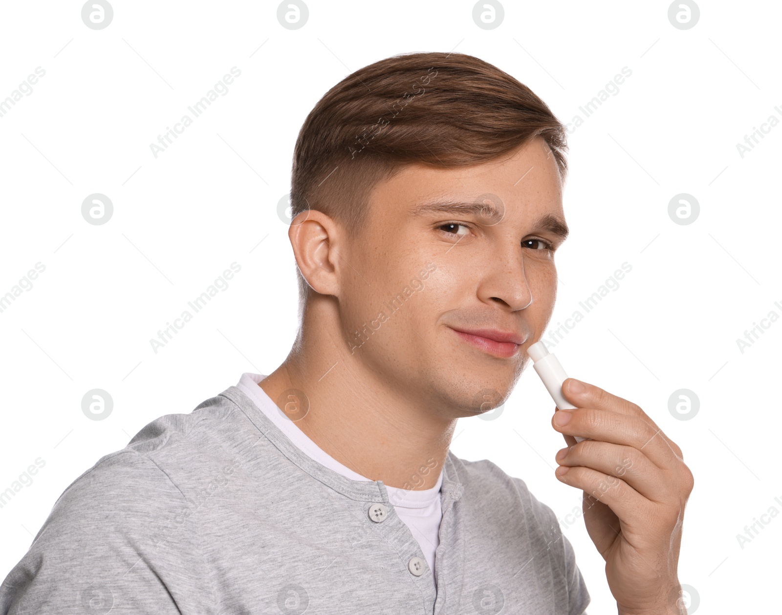 Young man applying lip balm onto his lips on white background Photo of Young man applying lip balm onto his lips on white background