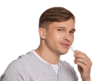 Photo of Young man applying lip balm onto his lips on white background