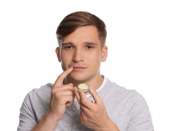 Photo of Young man applying lip balm onto his lips on white background