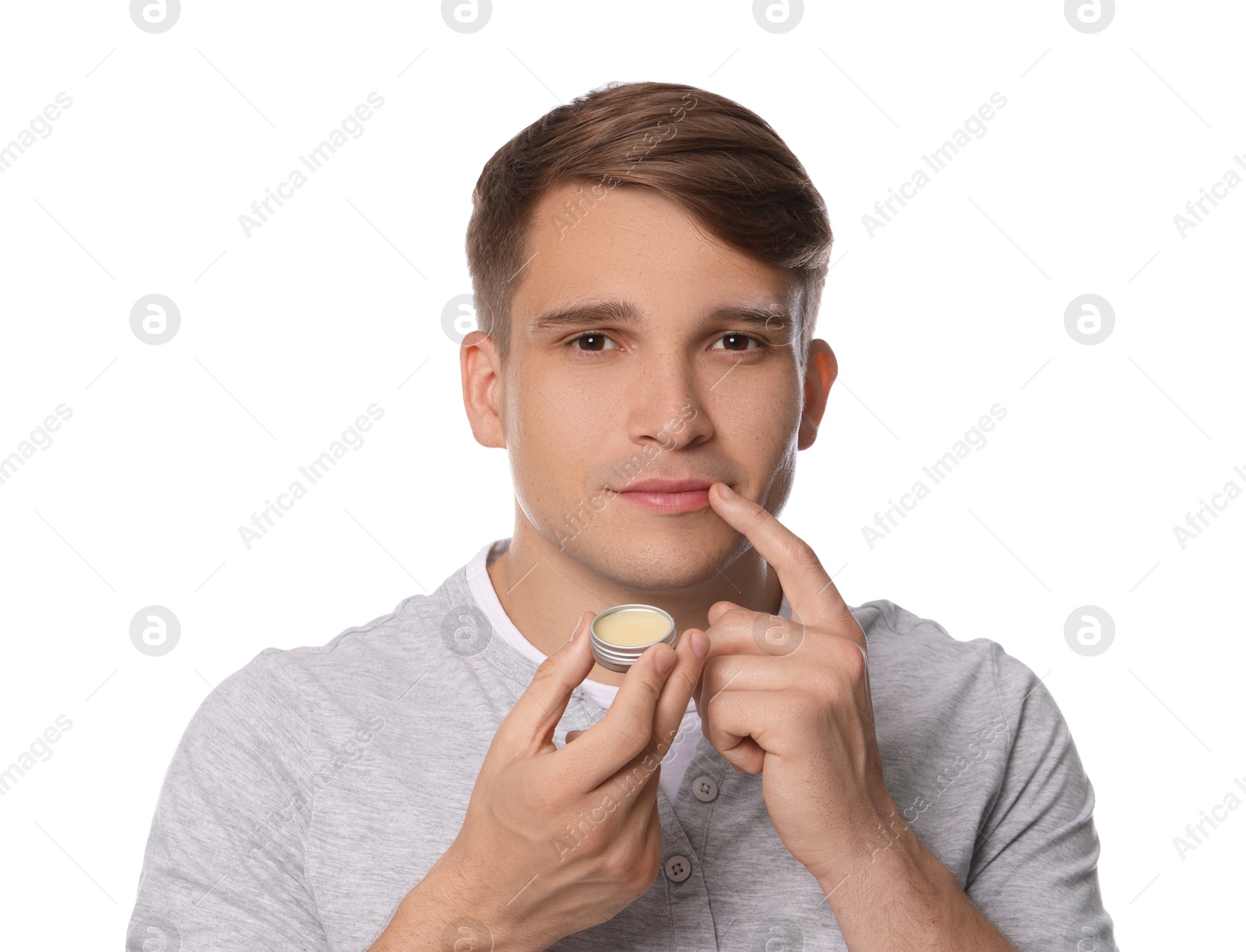 Young man applying lip balm onto his lips on white background Photo of Young man applying lip balm onto his lips on white background