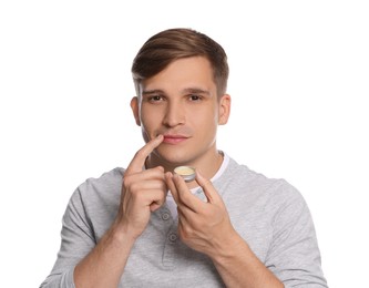 Photo of Young man applying lip balm onto his lips on white background