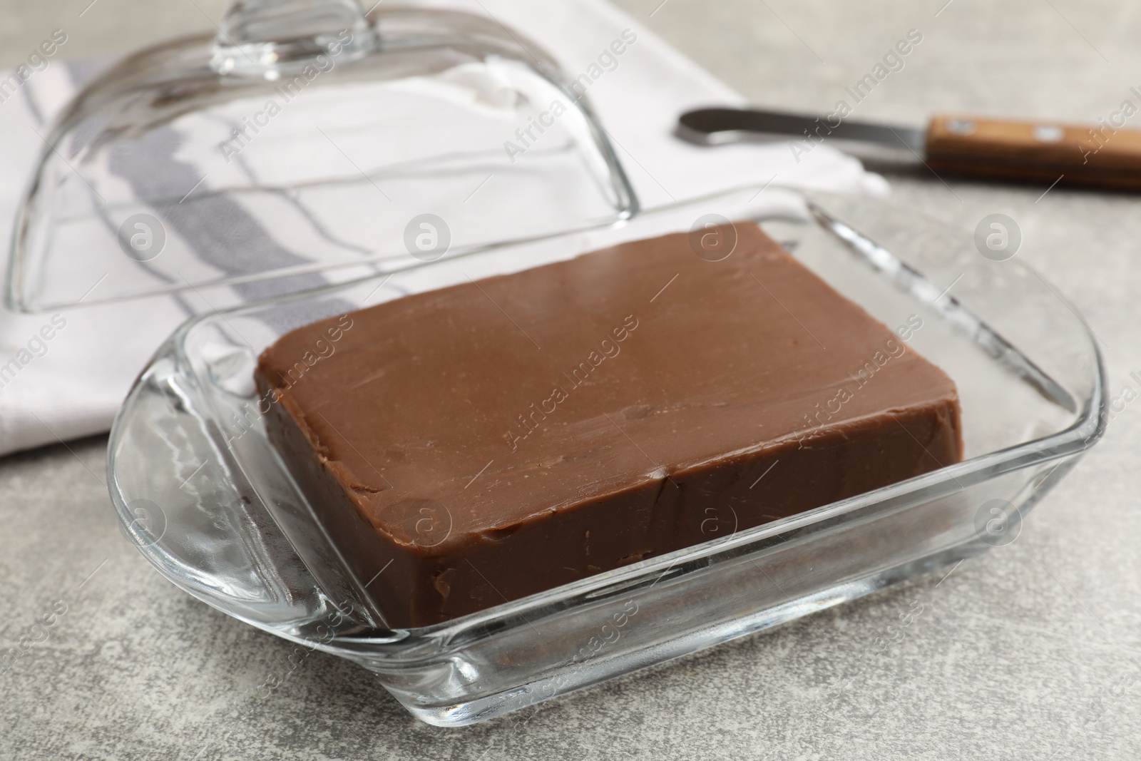 Block of tasty chocolate butter in glass keeper on grey textured table, closeup Photo of Block of tasty chocolate butter in glass keeper on grey textured table, closeup