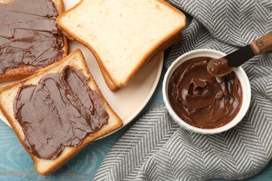 Photo of Tasty chocolate butter in bowl, slices of bread and knife on light blue wooden table, flat lay