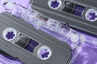 Photo of Audio cassettes with magnetic tapes on violet background, macro view
