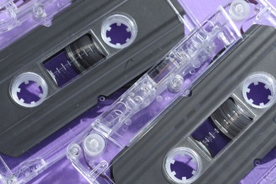 Photo of Audio cassettes with magnetic tapes on violet background, top view