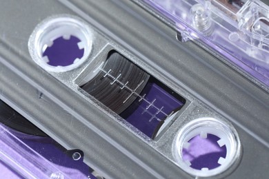 Photo of One audio cassette with magnetic tape on violet background, macro view