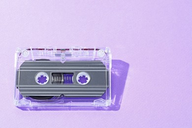 Photo of One audio cassette with magnetic tape on violet background, above view. Space for text