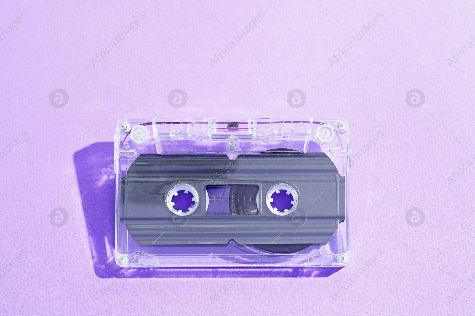 One audio cassette with magnetic tape on violet background, top view Photo of One audio cassette with magnetic tape on violet background, top view