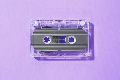 Photo of One audio cassette with magnetic tape on violet background, top view