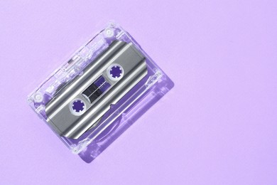 Photo of One audio cassette with magnetic tape on violet background, top view. Space for text