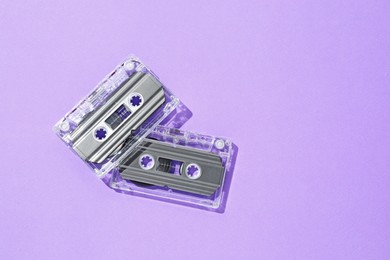 Photo of Audio cassettes with magnetic tapes on violet background, flat lay. Space for text