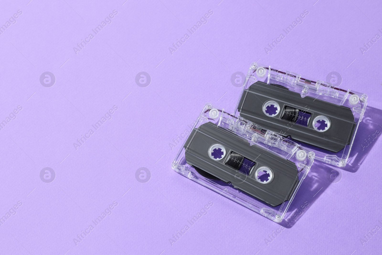 Audio cassettes with magnetic tapes on violet background, flat lay. Space for text Photo of Audio cassettes with magnetic tapes on violet background, flat lay. Space for text