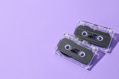 Photo of Audio cassettes with magnetic tapes on violet background, flat lay. Space for text