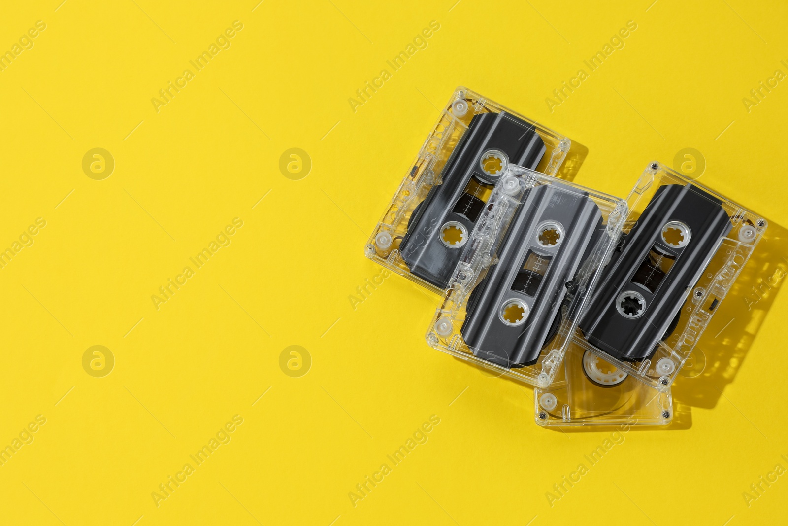 Audio cassettes with magnetic tapes on yellow background, above view. Space for text Photo of Audio cassettes with magnetic tapes on yellow background, above view. Space for text