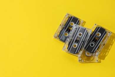 Photo of Audio cassettes with magnetic tapes on yellow background, above view. Space for text