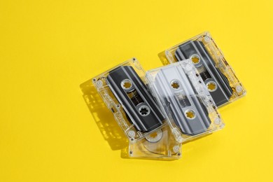 Photo of Audio cassettes with magnetic tapes on yellow background, above view. Space for text