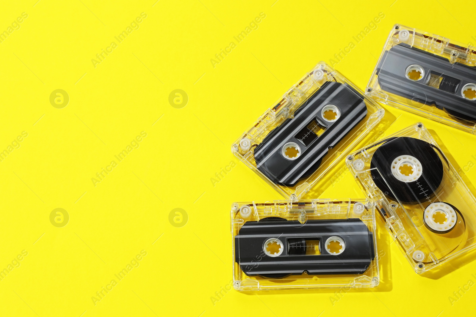 Audio cassettes with magnetic tapes on yellow background, above view. Space for text Photo of Audio cassettes with magnetic tapes on yellow background, above view. Space for text