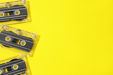 Photo of Audio cassettes with magnetic tapes on yellow background, flat lay. Space for text