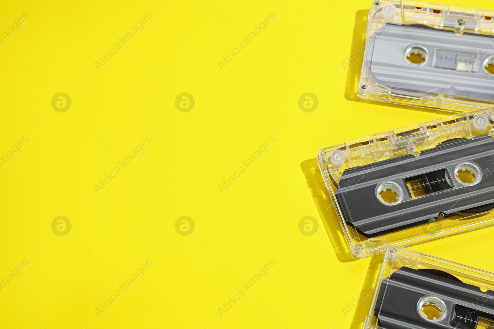 Audio cassettes with magnetic tapes on yellow background, above view. Space for text Photo of Audio cassettes with magnetic tapes on yellow background, above view. Space for text