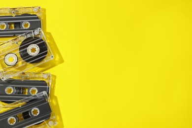 Photo of Audio cassettes with magnetic tapes on yellow background, flat lay. Space for text