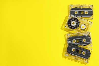 Photo of Audio cassettes with magnetic tapes on yellow background, flat lay. Space for text