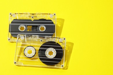 Photo of Audio cassettes with magnetic tapes on yellow background. Space for text