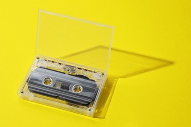 Photo of One audio cassette in open box on yellow background