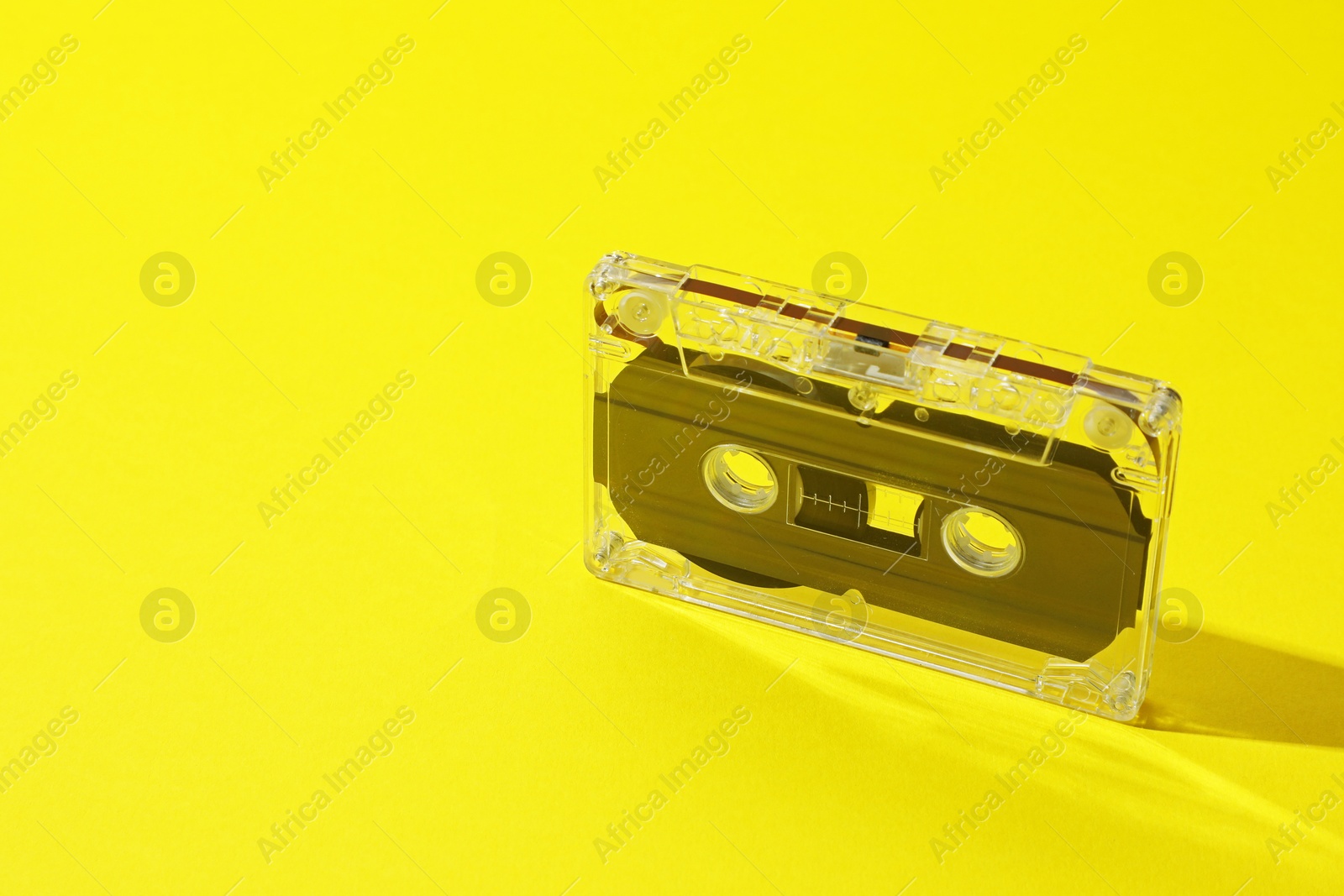 One audio cassette with magnetic tape on yellow background, closeup. Space for text Photo of One audio cassette with magnetic tape on yellow background, closeup. Space for text