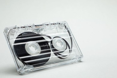 Photo of One audio cassette in air on light grey background, closeup