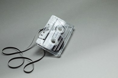 Photo of One audio cassette with magnetic tape on grey background, closeup