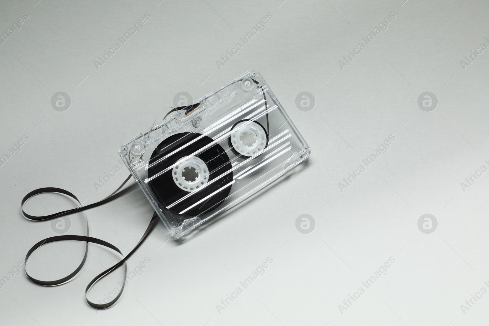One audio cassette with magnetic tape on grey background, above view Photo of One audio cassette with magnetic tape on grey background, above view