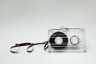 Photo of One audio cassette with magnetic tape on light grey background, closeup