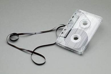 Photo of One audio cassette with magnetic tape on grey background, closeup