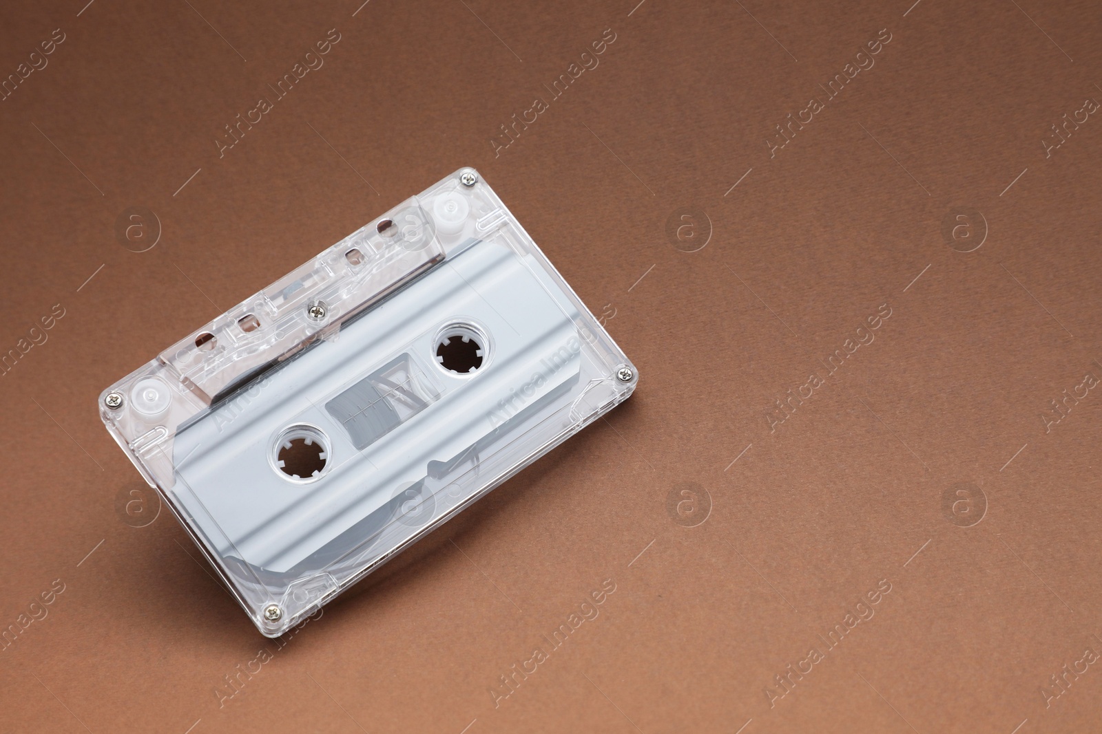 One audio cassette with magnetic tape on brown background, above view. Space for text Photo of One audio cassette with magnetic tape on brown background, above view. Space for text