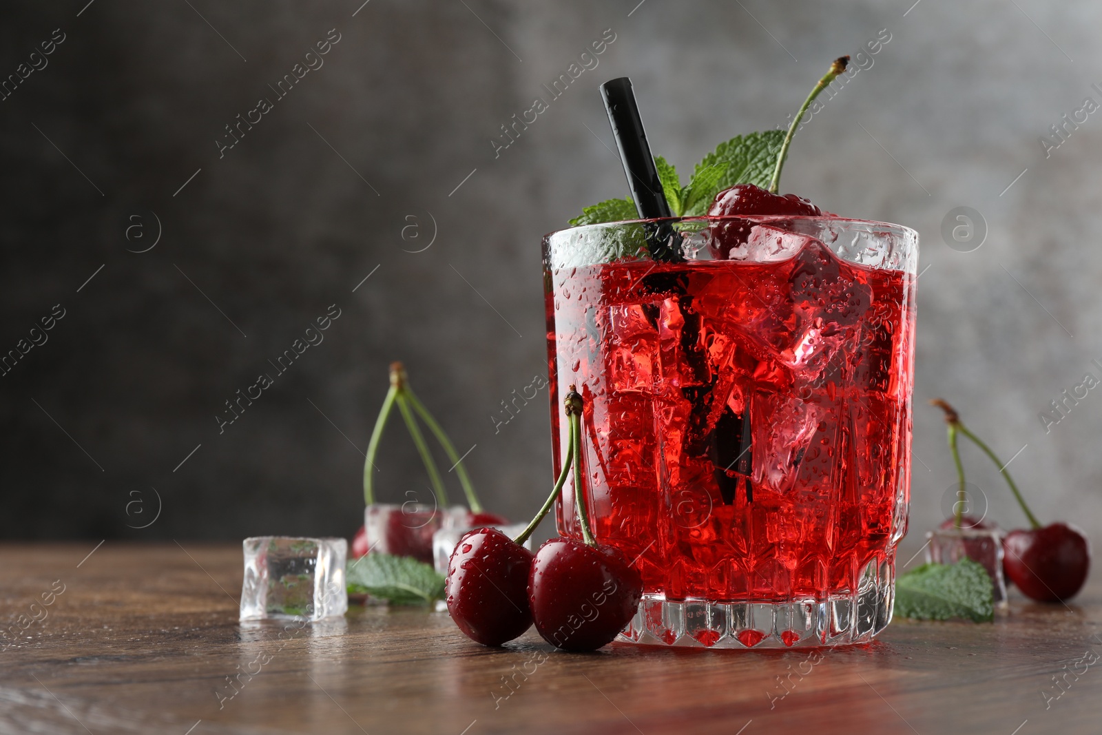 Tasty cherry soda with ice cubes, berries and mint in glass on wooden table, closeup. Space for text Photo of Tasty cherry soda with ice cubes, berries and mint in glass on wooden table, closeup. Space for text