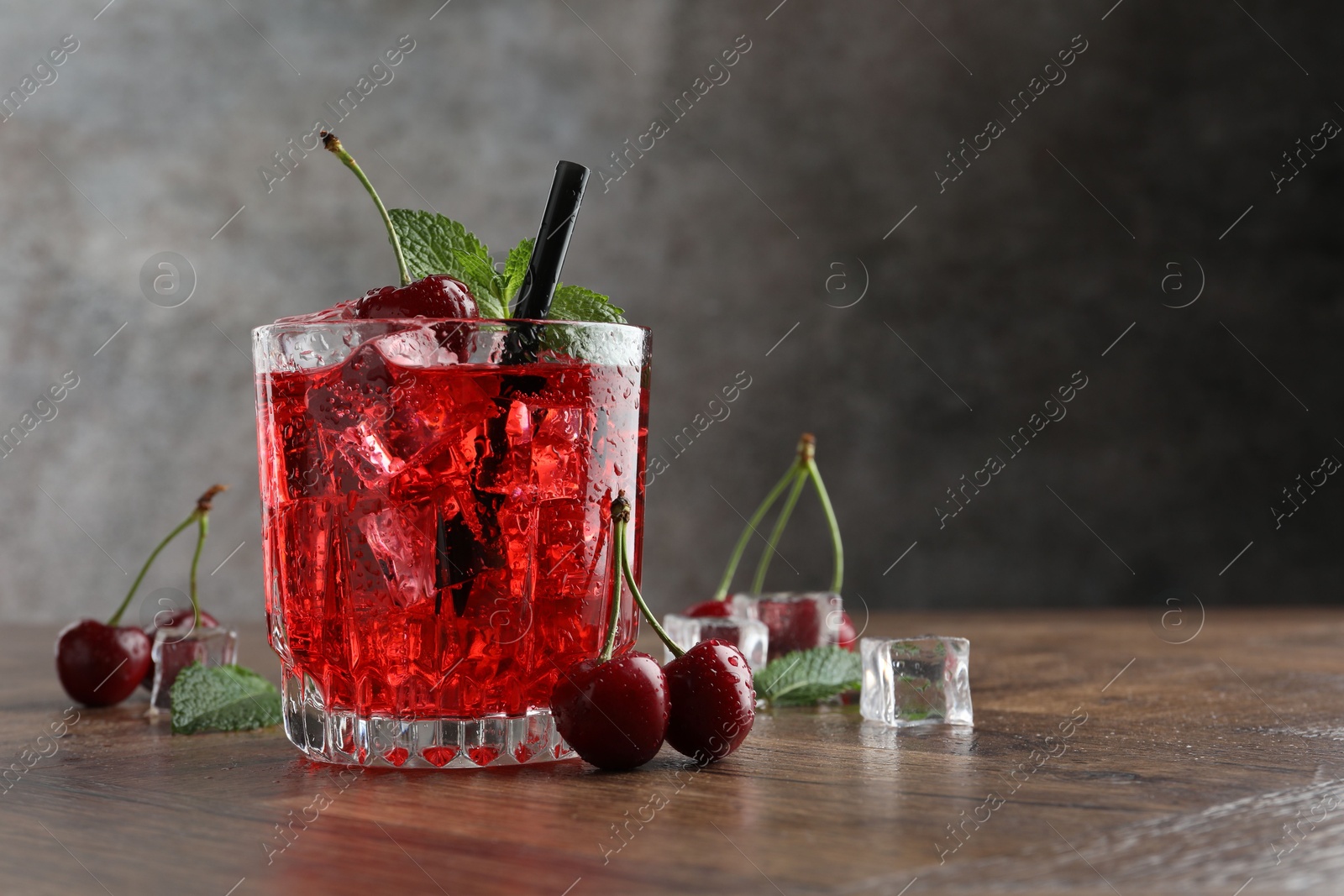 Tasty cherry soda with ice cubes, berries and mint in glass on wooden table, closeup. Space for text Photo of Tasty cherry soda with ice cubes, berries and mint in glass on wooden table, closeup. Space for text