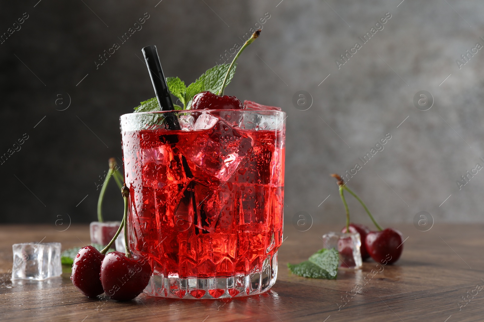 Tasty cherry soda with ice cubes, berries and mint in glass on wooden table, closeup. Space for text Photo of Tasty cherry soda with ice cubes, berries and mint in glass on wooden table, closeup. Space for text
