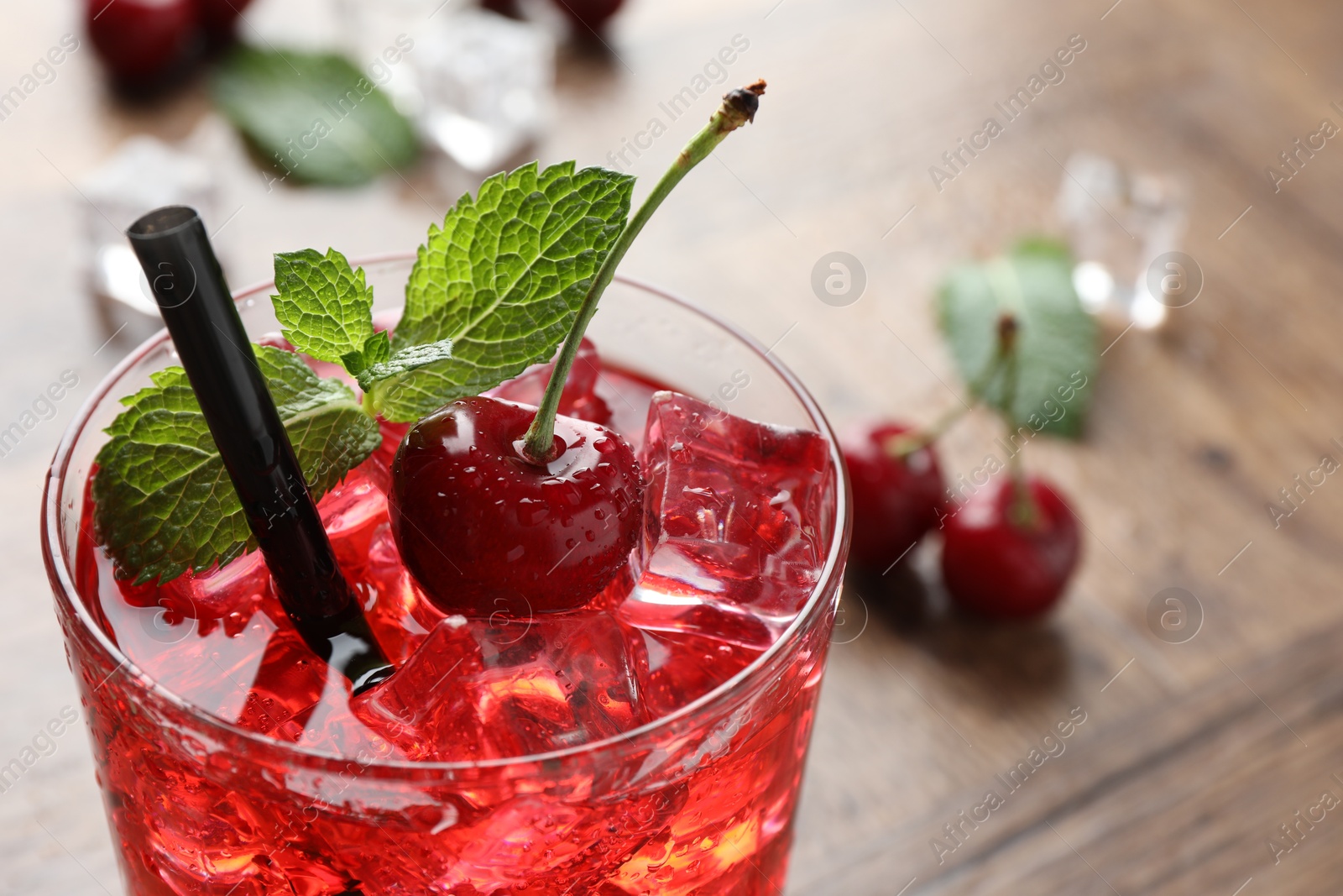 Tasty cherry soda with ice cubes, berries and mint in glass on wooden table, closeup. Space for text Photo of Tasty cherry soda with ice cubes, berries and mint in glass on wooden table, closeup. Space for text