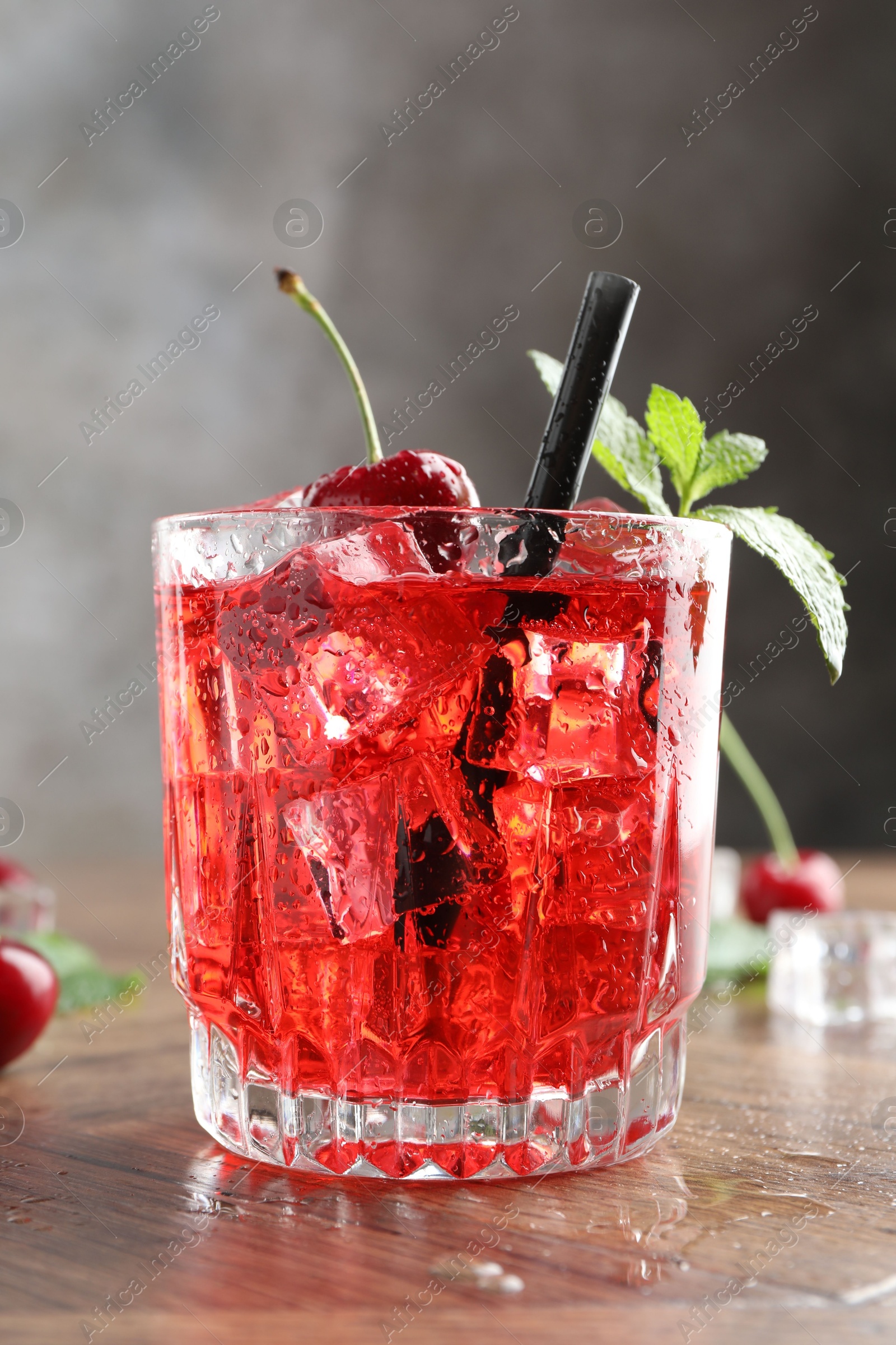Tasty cherry soda with ice cubes, berries and mint in glass on wooden table, closeup Photo of Tasty cherry soda with ice cubes, berries and mint in glass on wooden table, closeup