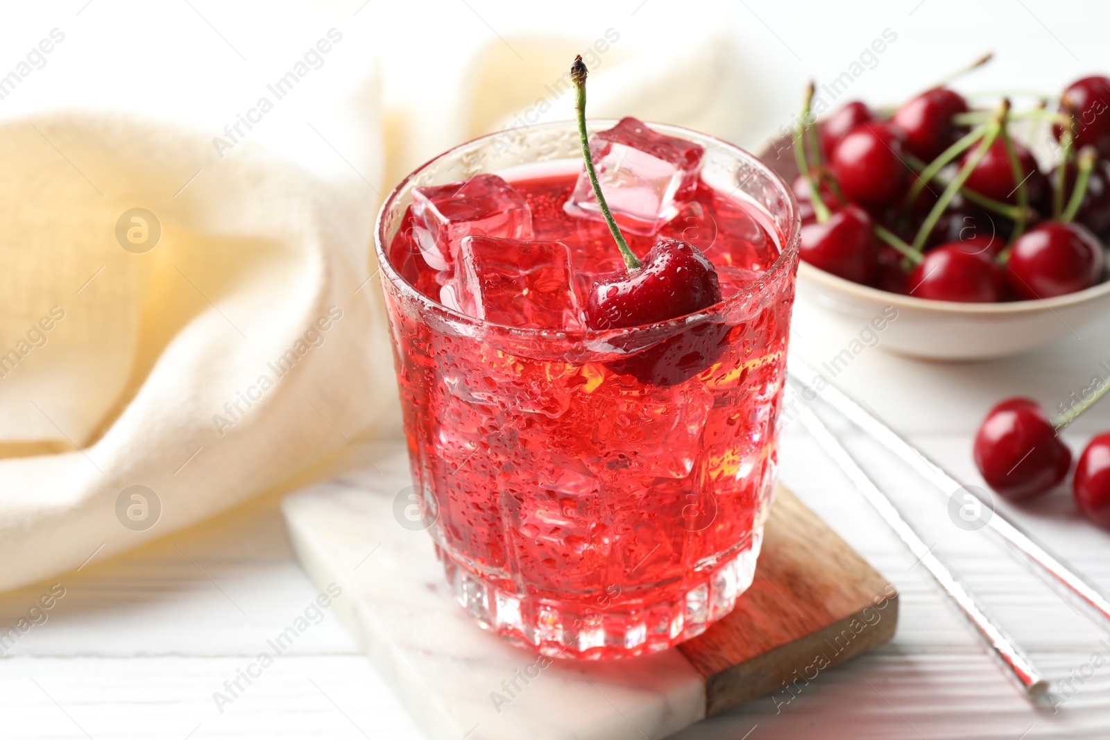 Tasty cherry soda with ice cubes and berries in glass on white wooden table, closeup Photo of Tasty cherry soda with ice cubes and berries in glass on white wooden table, closeup