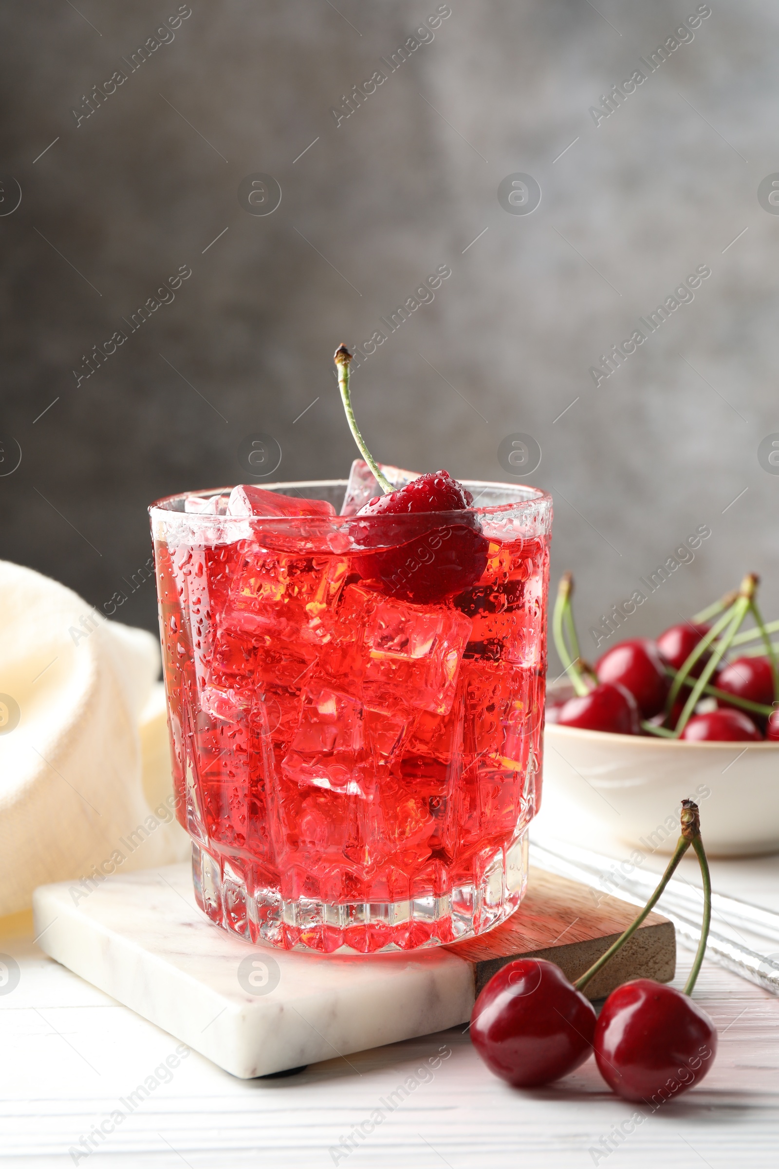 Tasty cherry soda with ice cubes and berries in glass on white wooden table, closeup Photo of Tasty cherry soda with ice cubes and berries in glass on white wooden table, closeup