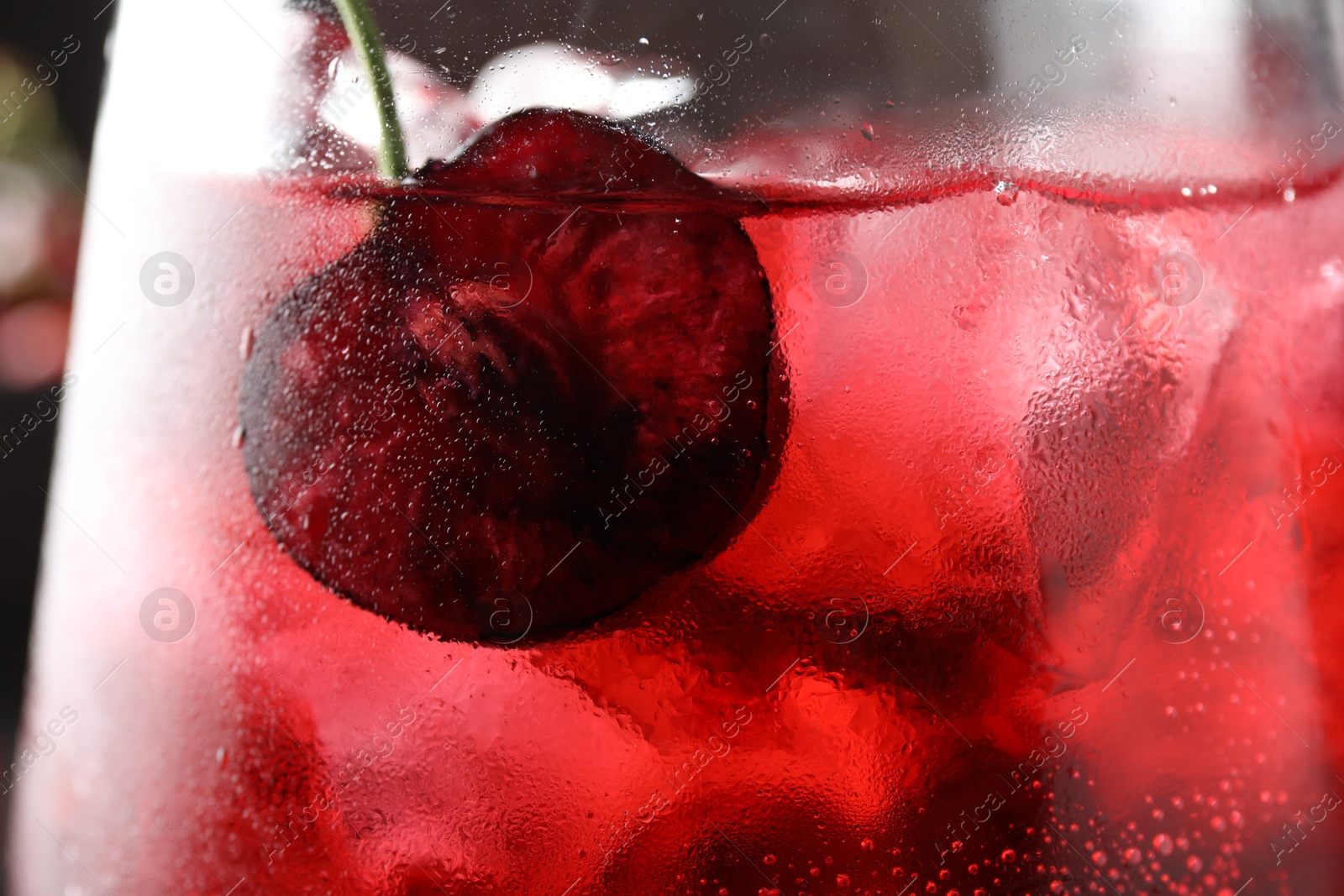 Tasty cherry soda with ice cubes and berry in glass, closeup Photo of Tasty cherry soda with ice cubes and berry in glass, closeup