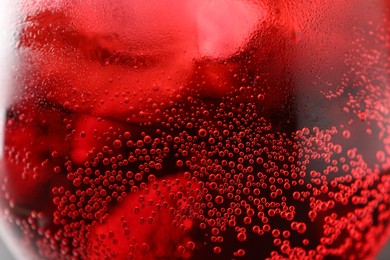Photo of Glass of tasty cherry soda with ice cubes and berry as background, closeup