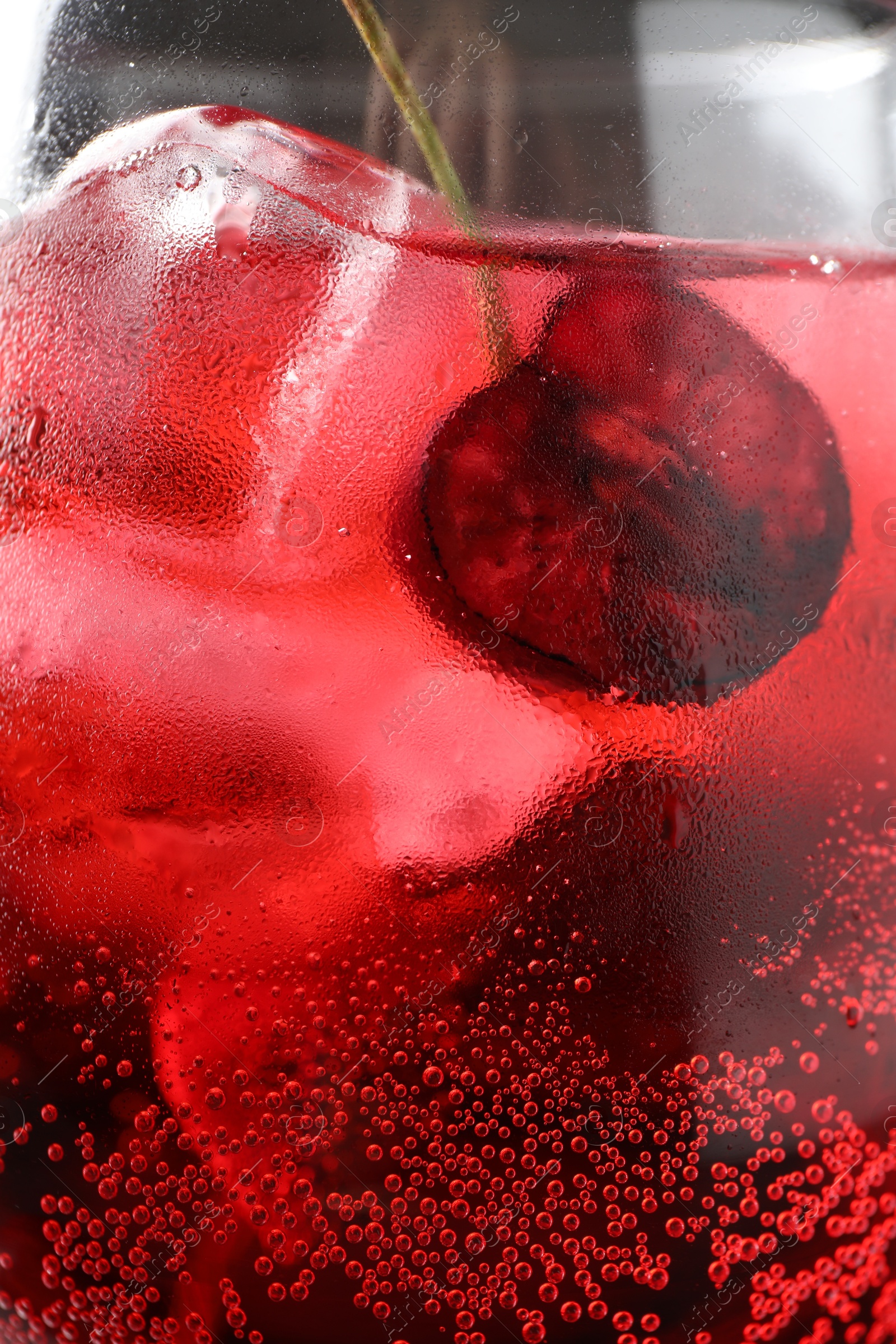 Tasty cherry soda with ice cubes and berry in glass, closeup Photo of Tasty cherry soda with ice cubes and berry in glass, closeup