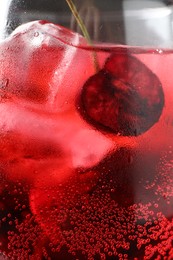 Photo of Tasty cherry soda with ice cubes and berry in glass, closeup